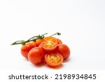 Small photo of Deep red cherry tomatoes with green branch one in cut with seeds and juice on white background eat a very healthy salad or simply a tomato with a pinch of salt and olive oil.