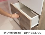 Woman open shelf, pull open drawer wooden in cabinet.