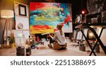 Small photo of Back view of talented concentrated Caucasian woman professional artist sitting on floor in studio in evening painting drawing on big canvas, creativity work, contemporary creative painter