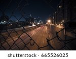 Night city skyline through the wire mesh fence