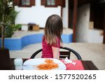 Small photo of Caucasian Girl child turns away from a plate with pasta with tomato sauce in a cafe on the street, poor behavior at the table, ill-bred child. Children's crisis and protest