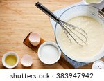Ingredients for making pancakes - egg, butter, milk, sugar and raw dough for pancakes on wooden background. Rustic or rural style. Top view with free text space
