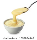 Small photo of Pouring condensed milk with spoon isolated on white background with clipping path, delicious flowing creamy evaporated cream