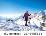 Small photo of St. Anton am Arlberg. March 10, 2022. Young man holding snowboard while standing on top of snowy mountain, Snowboarder stands on the background of beautiful view of snowcapped mountains