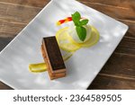 Small photo of valrhona chocolate terrine with yuzu sorbet, fresh mint and pistachio cream dessert on a white plate natural light