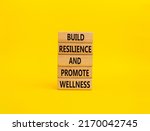 Build Resilience and Promote Wellness symbol. Wooden blocks with words Build Resilience and Promote Wellness. Beautiful yellow background. Build Resilience and Promote Wellness. Copy space