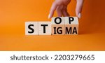 Small photo of Stop and Stigma symbol. Concept words Stop and Stigma on wooden cubes. Beautiful orange background. Businessman hand. Business and Stop and Stigma concept. Copy space.