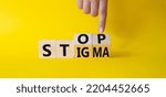 Small photo of Stop and Stigma symbol. Businessman hand points at wooden cubes with words Stop and Stigma. Beautiful yellow background. Businessman hand. Business and Stop and Stigma concept. Copy space.