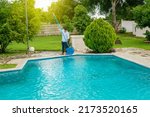 Small photo of Man cleaning a swimming pool with skimmer, maintenance person cleaning a swimming pool with skimmer, swimming pool cleaning and maintenance concept.