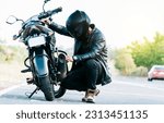 Small photo of Motocyclist fixing the motorcycle on the road. Biker repairing motorcycle on the road, Man checking his motorcycle on the road