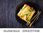 Small photo of blintz, rolled filled with sweetened cottage cheese pancakes or crepes on a plate on a wooden table, horizontal view from above, flat lay