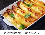 Small photo of blintz, rolled filled with sweetened cottage cheese pancakes or crepes in a baking dish on a wooden table, horizontal view from above