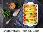 Small photo of blintz, rolled filled with sweetened cottage cheese pancakes or crepes in a baking dish on a wooden table, horizontal view from above, flat lay