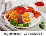 Small photo of fried eggs, rasher or bacon slices, potato farls, grilled tomatoes and fresh lettuce on white plate with fork on white wooden table, ireland breakfast, close-up