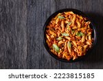 Whole wheat pasta bake with ground beef and melted red cheddar cheese on black  baking dish on dark wood table, landscape view from above, flat lay, free space