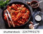 Chicken Chasseur, hunter chicken, poulet saute chasseur, chicken stew with mushrooms in tomato sauce in black bowl on wooden table, french cuisine