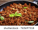 close-up of hot juicy ground beef stewed with tomato sauce, spices, basil, finely chopped vegetables and celery in frying pan, classic recipe, side view from above