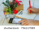 Christmas holiday shopping lists and sale season concept. Hand holding pen using calculator. to write shopping lists for friends and family planning budget for holiday with shopping cart and gift box