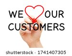 Hand writing We Love Our Customers with marker on transparent wipe board. Customer satisfaction, appreciation and kindness concept.