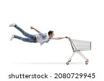 Full length shot of a casual guy man flying and holding an empty shopping cart isolated on white background