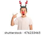 Cheerful boy posing with red reindeer ears and a red nose and pointing at them isolated on white background