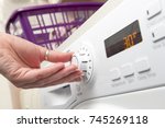 Hand adjusting the temperature setting of a clothes dryer by turning a knob
