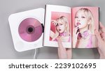 Small photo of Fan hands holding BlackPink BORN PINK 2nd Album photobook with Rose on grey. Pink music CD in player. South Korean girl group BlackPink. Space for text. Gatineau, QC Canada - November 10 2022.