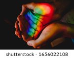Teenage boy holding rainbow in his hands