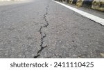 Small photo of Cracked asphalt road surface background. Surface texture of old asphalt road with cracks. Alligator type cracking in the asphalt pavement. Cracks on asphalt in a sunny day.