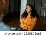 Small photo of Portrait of youthful pretty african american female sitting on bed with arrogant resentful facial expression listening to his boyfriend and looking aside with annoyance. Selective focus