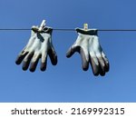Washed work gloves fixed with clips hang on a rope  against the blue sky
