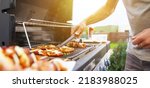 Small photo of Young man grilling some kind of meats on the gas grill during lovely summer time, food concept