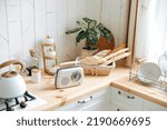 A wooden worktop filled with kitchen utensils, a retro radio and fresh baked goods in a bright Scandinavian kitchen. Modern white kitchen
