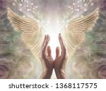 Sensing Angelic Energy - Male hands reaching up into a beautiful pair of golden Angel wings with white light and sparkles flowing  between, against a warm ethereal energy formation background
