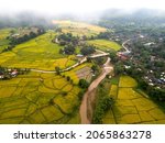 Top view Aerial photo from flying drone over paddie rice fields and rural village  in Chiang Mai province, Thailand.Top view beautiful Sunset and Mountain with Fog.