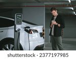 Small photo of Young man travel with EV electric car to shopping center parking lot charging in downtown city showing urban sustainability lifestyle by green clean rechargeable energy of electric vehicle innards