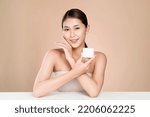 Small photo of Ardent woman smiling holding mockup product for advertising text place, light grey background. Concept of healthcare for skin, beauty care product for advertising.