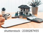 Small photo of House model is displayed on wooden meeting table with in the blurred background of real estate agent and client discuss terms and conditions of house loan or rental lease contract. Entity