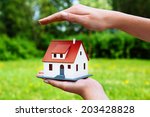 Home insurance concept.Photo of a hand hovering over a miniature house