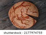 Small photo of Large round loaf of bread with a piece cut out on black wooden table. Dark HDR photo. Simple food, meager food, poverty and malnutrition