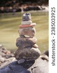 Small photo of Pile of Balanced Stones Cairn - Smooth stones stacked into a cairn along the edge of a body of water symbolize balance and harmony