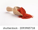 Red chilli powder in a wooden measuring scoop or spoon on a white background