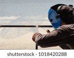 Small photo of Technician industrial worker welding metal steel create a chair. Flash burn, ultraviolet light, sparks, infrared light effect, technician use welding mask to protect the eyes. Industry concept.