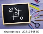 Small photo of Tic-Tac-Toe on the school board. Game of Noughts and Crosses played on chalk board. Educational games for kids. Concept break time in school and business. Mind training, brainstorming.