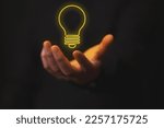 Small photo of hand holding bright light bulb, as a representation of an idea, on black background, theme creativity, business, recursion.