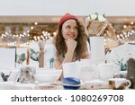 Young hipster woman selling behind counter with her ceramics and porcelain hand-painted at local market of craftsmen, small business