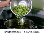 Hands cooking peas in a pot. 