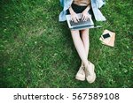 Top view of woman sitting in park on the green grass with laptop, notebook and smartphone, hands on keyboard. Computer screen mockup. Student studying outdoors. Copy space for text