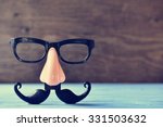 a fake mustache, nose and eyeglasses on a rustic blue wooden surface