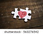 closeup of two pieces of a puzzle forming a heart on a rustic wooden surface, depicting the idea of that love is a thing of two